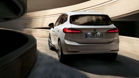 Динамичный дизайн задней части BMW 2 серии Active Tourer U06 2021 BMW 2 серии Active Tourer U06 2021 в цвете Mineral White металлик, вид сзади на спиральную рампу на автостоянке