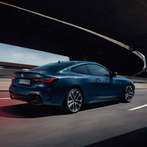 Вид модели BMW 4 серии Coupe G22 2020 года сбоку с поворотом в три четверти BMW 4 серии Coupe G22 2020 года, цвет «Синий Арктик Рэйс Арктик Рэйс» металлик, вид сбоку в движении с поворотом в три четверти