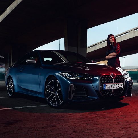 Мужчина стоит рядом с BMW M440i xDrive Coupe G22 (2020), вид сбоку с поворотом в три четверти Модель рядом с BMW M440i xDrive Coupe G22 (2020), Синий Арктик Рэйс металлик, вид сбоку с поворотом в три четверти