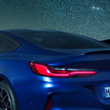 Задний спойлер М BMW M8 Competition Coupé в Marina Bay Blue металлик, ночная съемка плечевой части с задним спойлером M в карбоне.