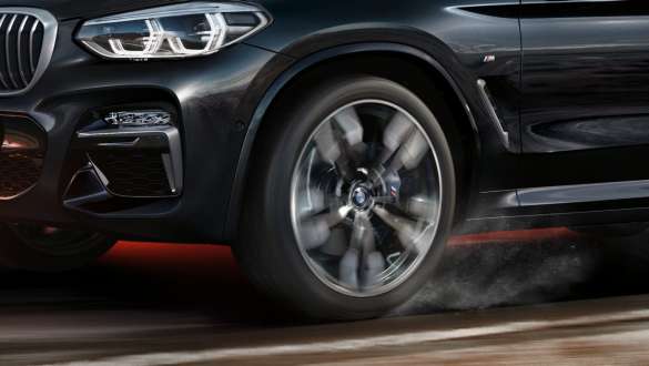 BMW X3 M40i, вид сбоку. BMW X3 M40i в Black Sapphire металлик, за рулем, экстерьер, вид сбоку с крутящимися легкосплавными дисками.