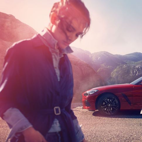 BMW Z4 Родстер перед видом на горы Мужчина с женщиной и BMW Z4 Roadster перед видом на горы