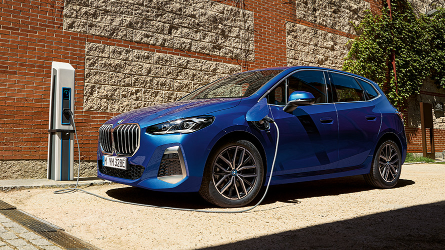 BMW 2 серии Active Tourer плагин-гибрид U06 2021 на зарядной станции BMW 2 серии Active Tourer 230e плагин-гибрид U06 2021 M в цвете Portimao Blue металлик, вид в три четверти сбоку на зарядной станции
