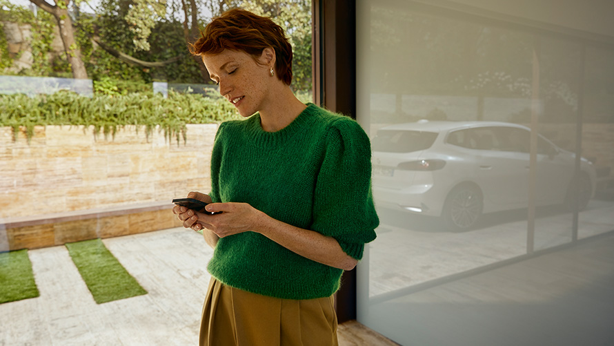 BMW Service Inclusive женщина, держащая смартфон Женщина, держащая смартфон на BMW Service Inclusive