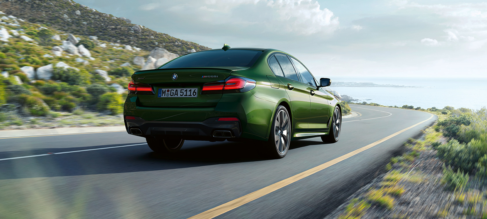 BMW M550i xDrive G30 LCI Facelift 2020, вид сзади в три четверти, в движении BMW M550i xDrive G30 LCI Facelift 2020, BMW Individual "Зеленый Эрмес металлик", вид сзади в три четверти, в движении