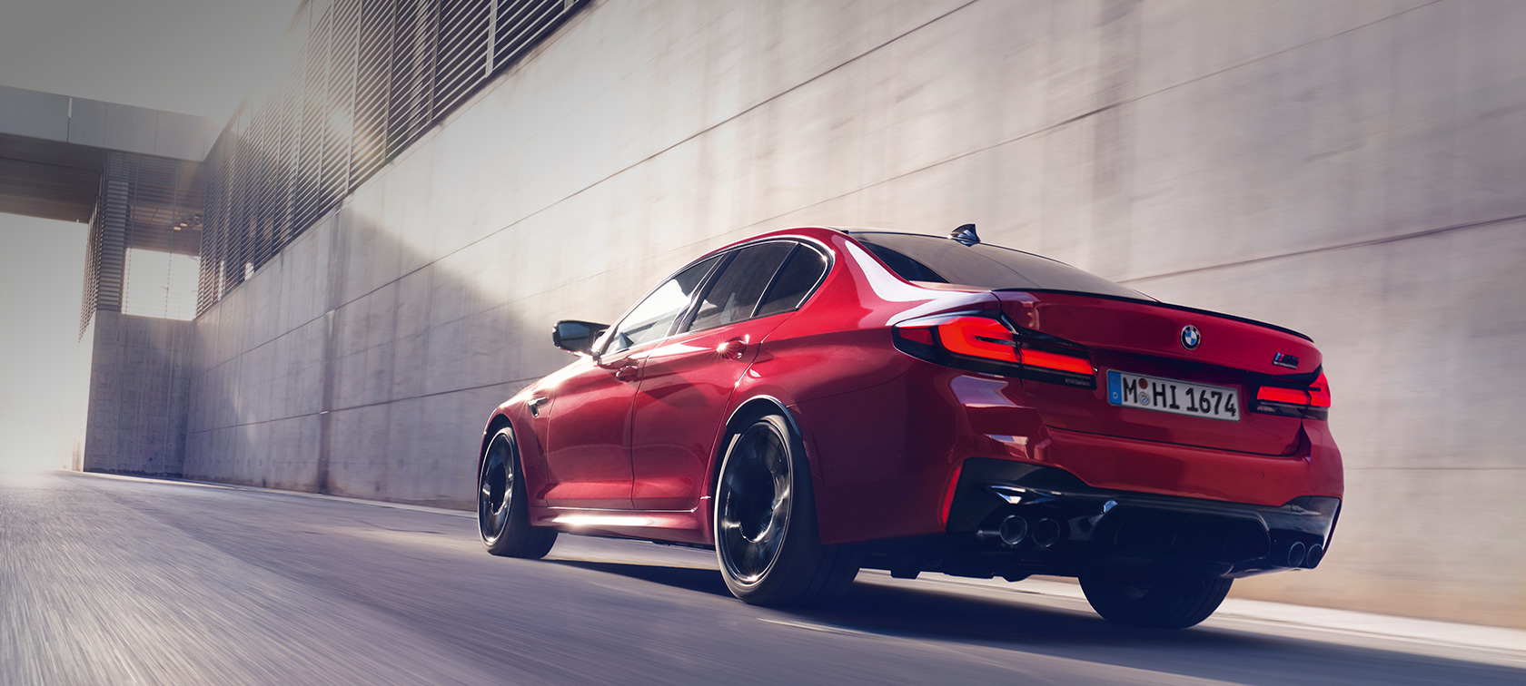 BMW M5 Competition F90 LCI Обновление 2020 г., вид сзади в три четверти, в движении BMW M5 Competition F90 LCI Обновление 2020 г. BMW Individual "Красный Имола", вид сзади в три четверти, в движении