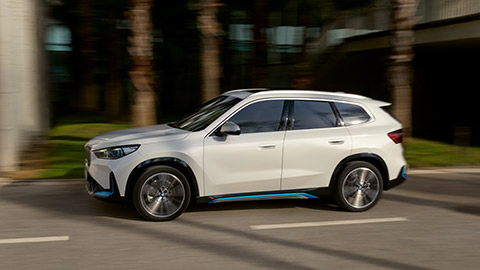 BMW iX1 U11, вид сбоку в движении по дороге BMW X Серии BMW iX1 U11, вид сбоку в движении по дороге