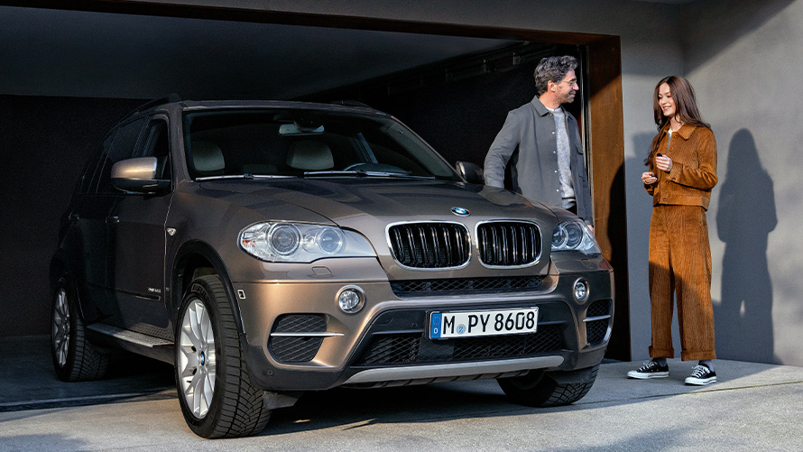 BMW Value Service Программа BMW Value Service BMW X2 G05 Мужчина и женщина стоят рядом с автомобилем BMW на подъездной дороге к гаражу
