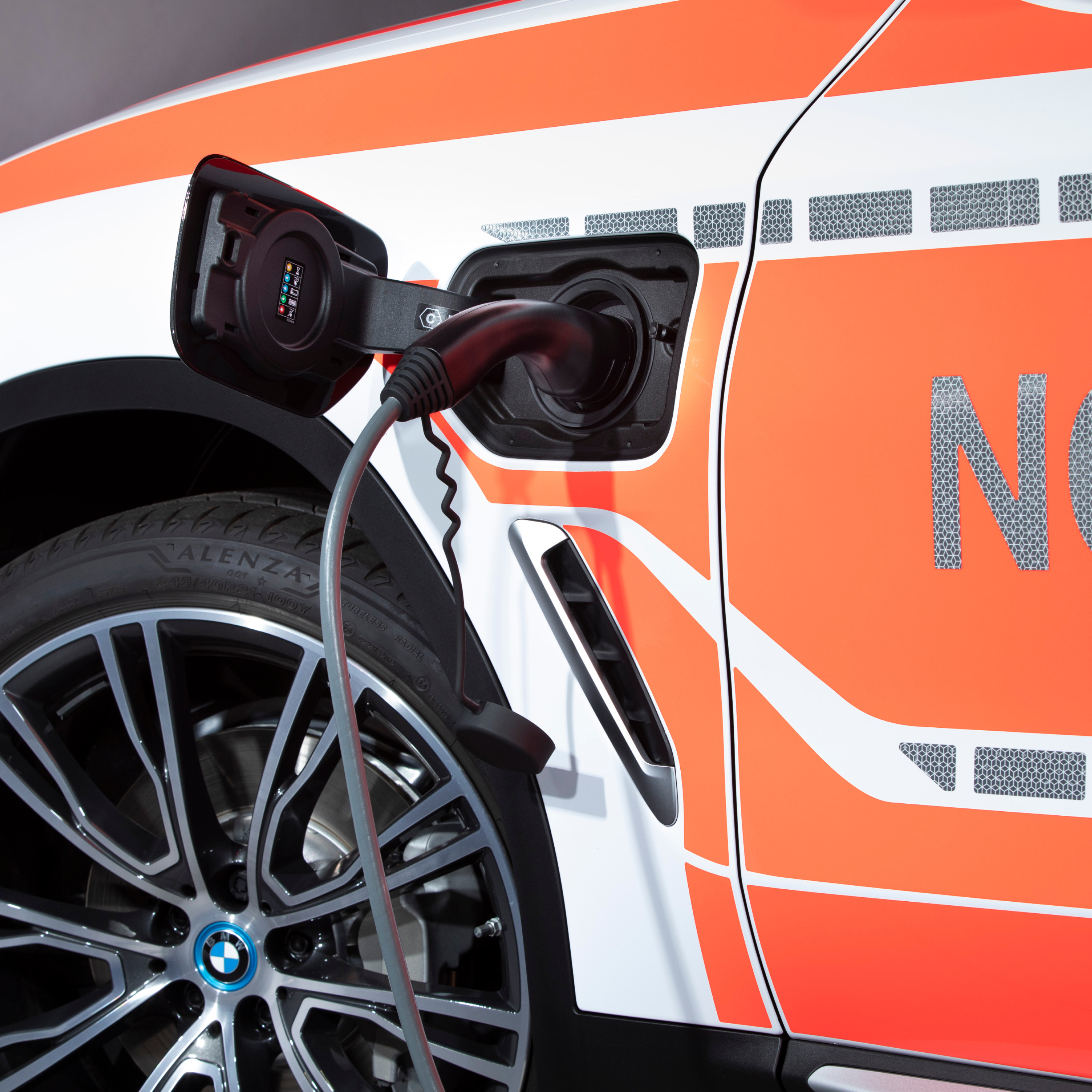 Автомобиль спецназначения BMW с подключаемым гибридом в процессе зарядки; крупный план зарядного кабеля