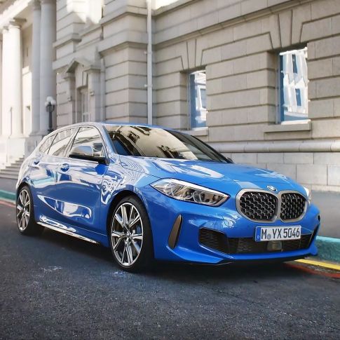 BMW 1 серии, вид спереди с поворотом в три четверти на обочине. BMW 1 серии в цвете Misano Blue металлик, вид спереди с поворотом в три четверти, парковка на обочине.